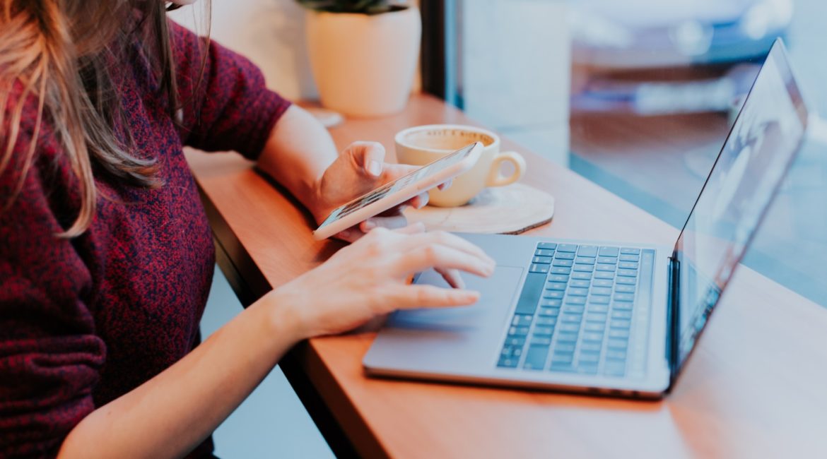 woman on laptop and phone in café