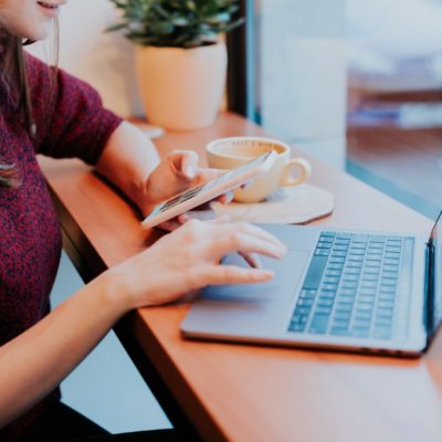 woman on laptop and phone in café