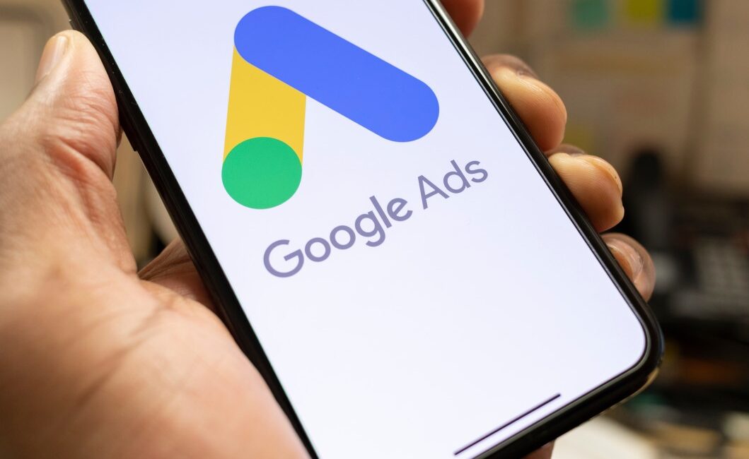 Man holding phone with google ads on screen