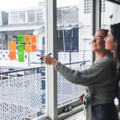 Two business professionals reviewing business marketing goals written on sticky notes