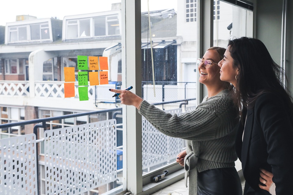 Two business professionals reviewing business marketing goals written on sticky notes