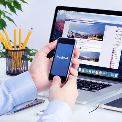 A business man monitoring Facebook Ads on a laptop and phone.